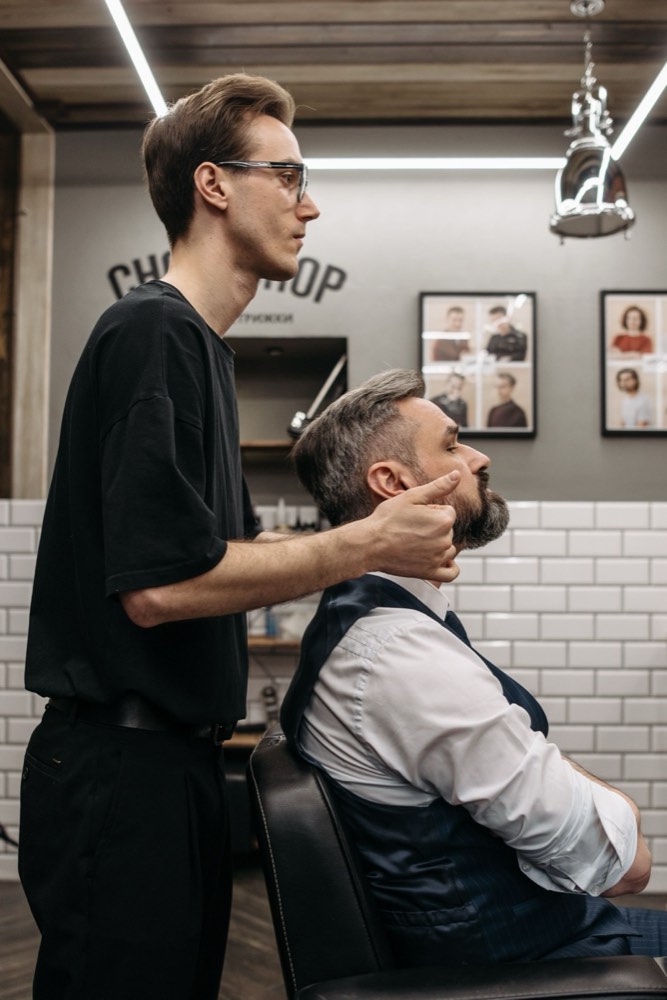 A barber shaping a client's beard