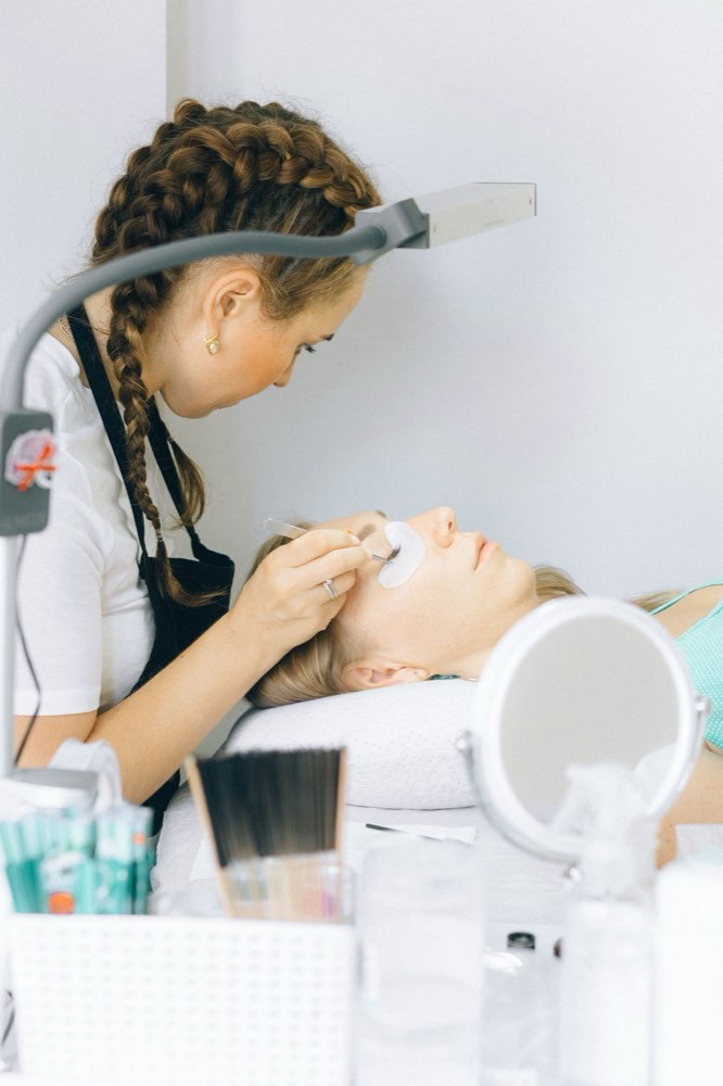 A lash technician working on a client