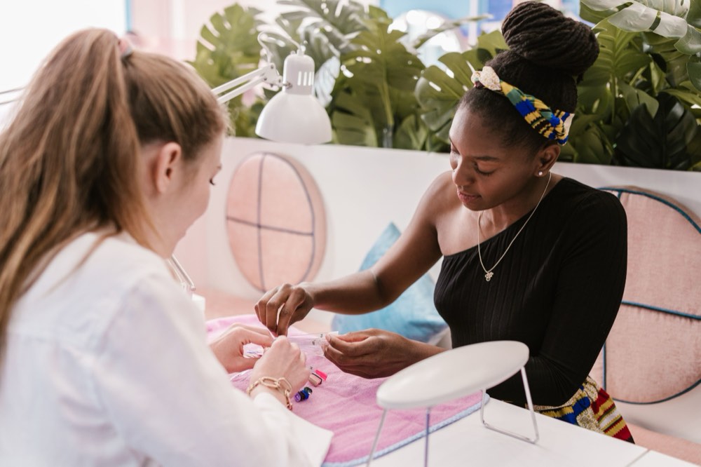 A nail technician choosing a colour with her client